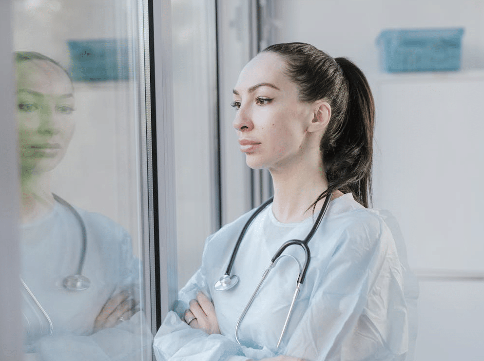 Healthcare worker looking out a window with arms crossed