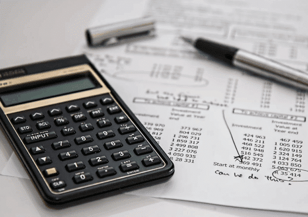 Black calculator near some cost sheets and black ballpoint pen